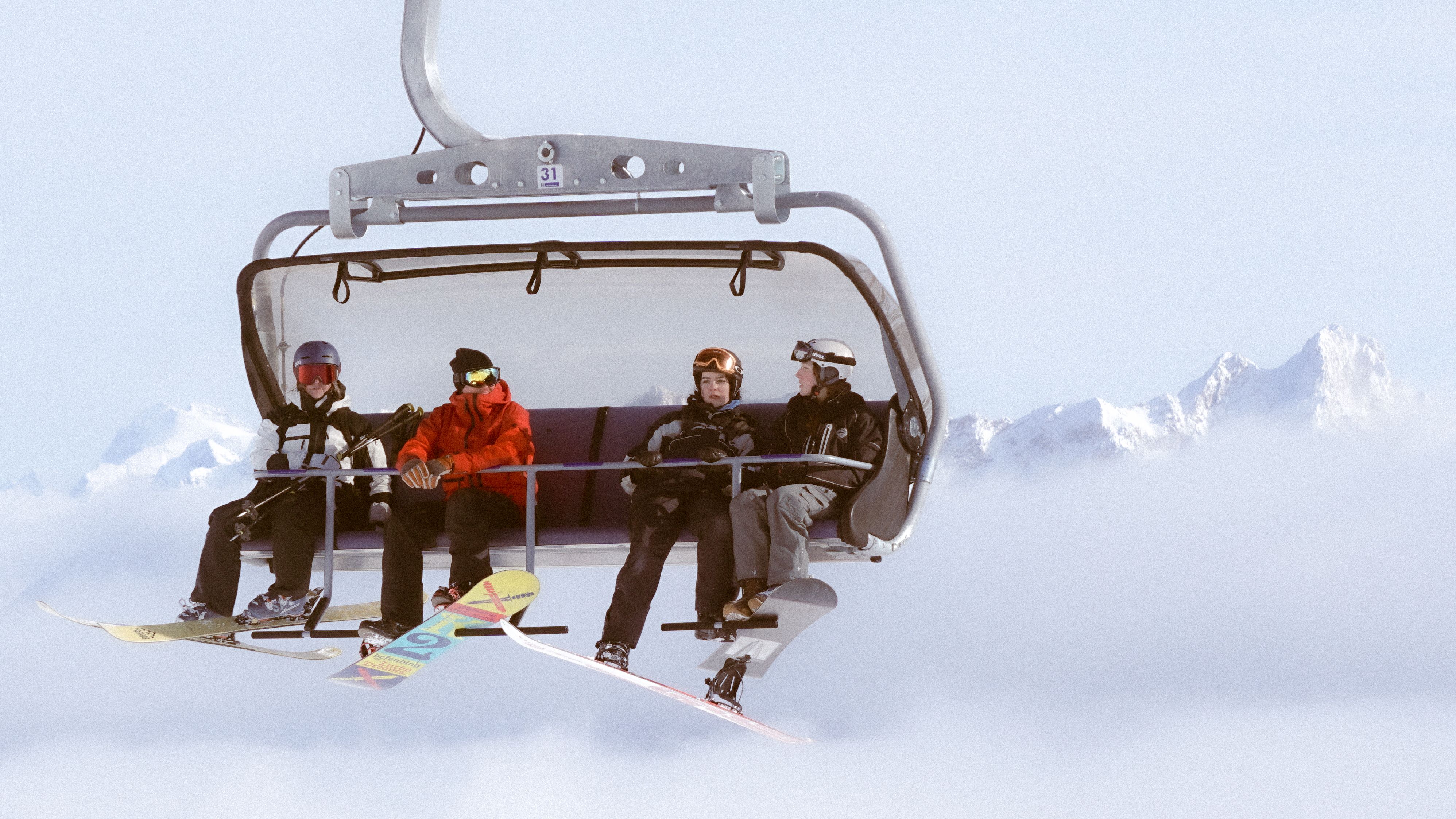 Grupo de esquiadores em um teleférico diante de montanhas nevadas.