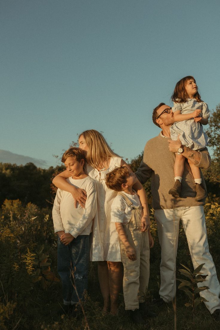 Família com três crianças reunida ao ar livre durante uma viagem.
