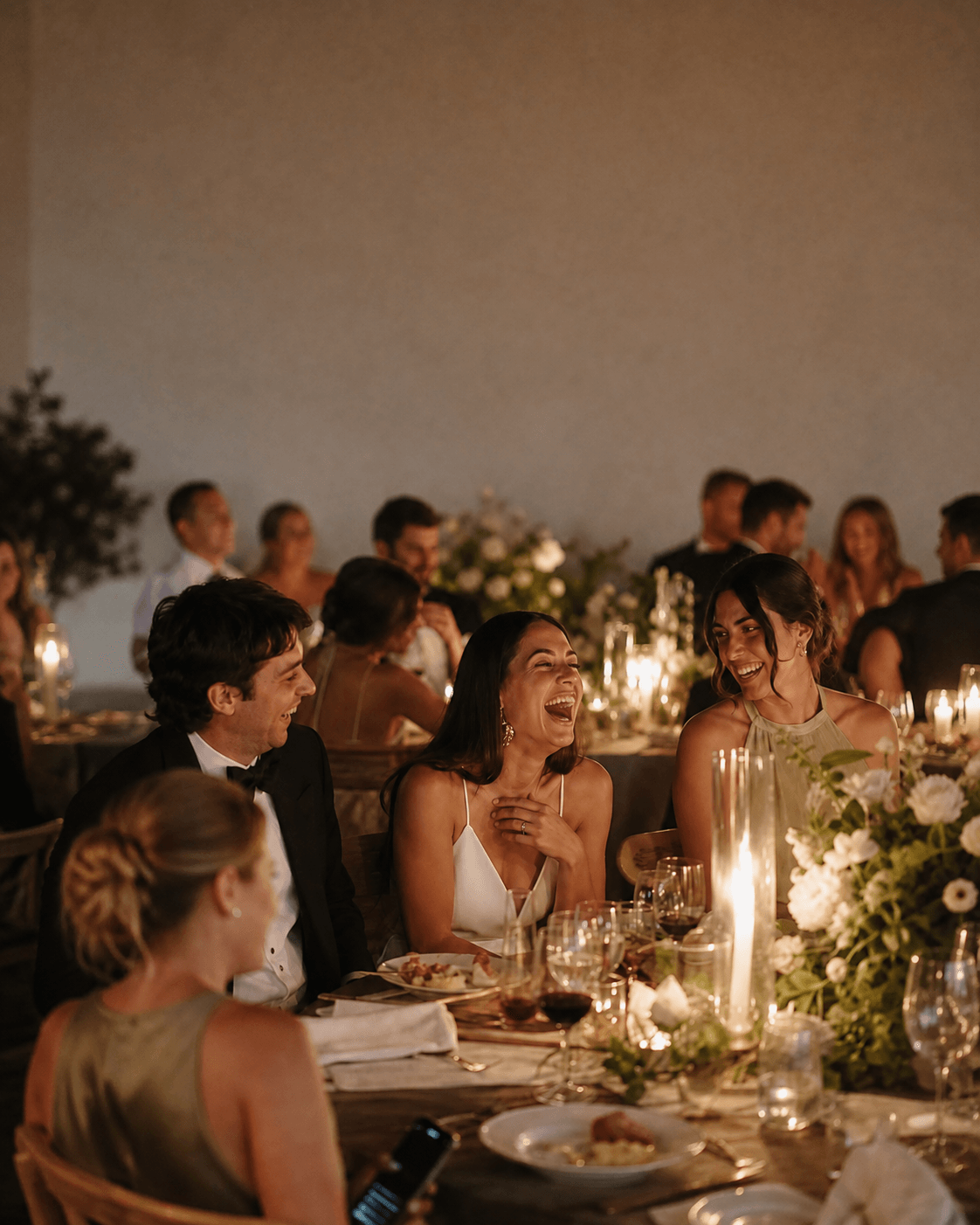 Convidados conversam e riem durante um jantar à luz de velas.