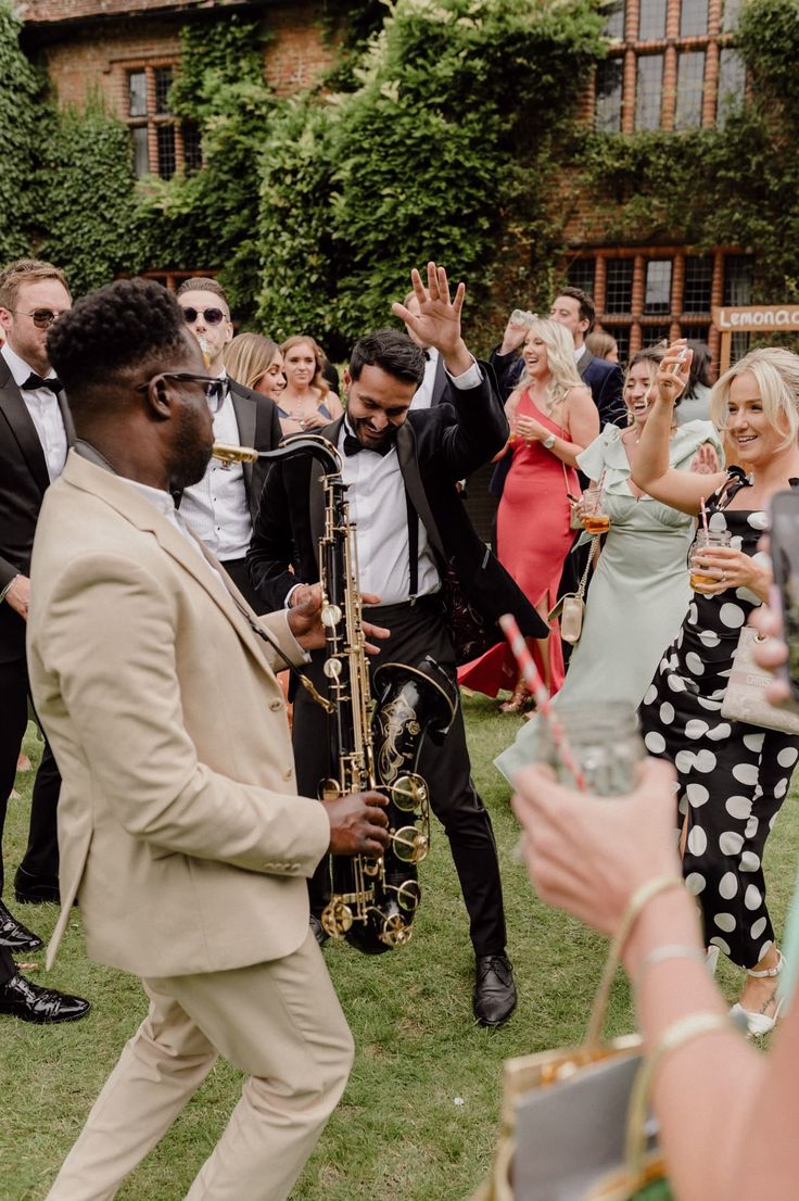Convidados dançam ao som de saxofone em uma celebração ao ar livre.